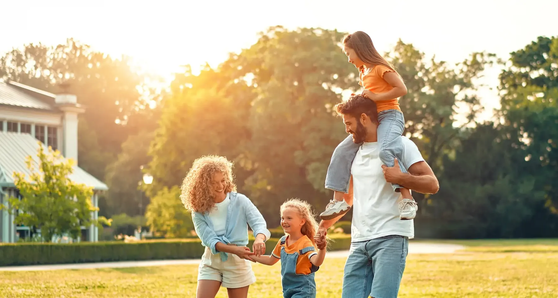Familie im Garten vor dem Eigenheim bei Sonnenuntergang