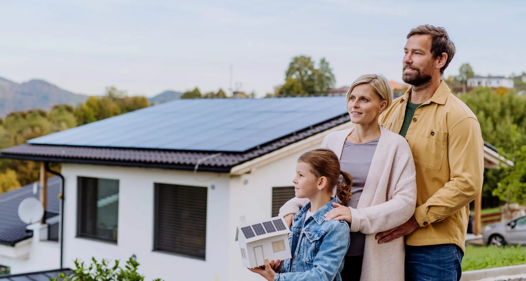 Familie vor ihrem Haus mit Photovoltaik-Anlage auf dem Dach